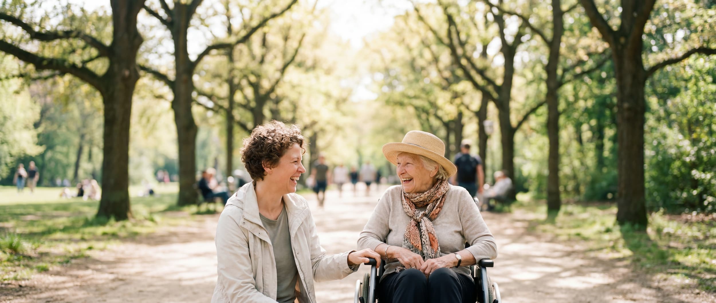Ativo caregiver laughing with a senior client in a wheelchair during an outdoor outing